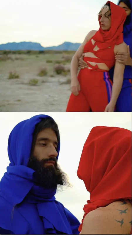 Dos bailarines envueltos en telas roja y azul en un paisaje árido.