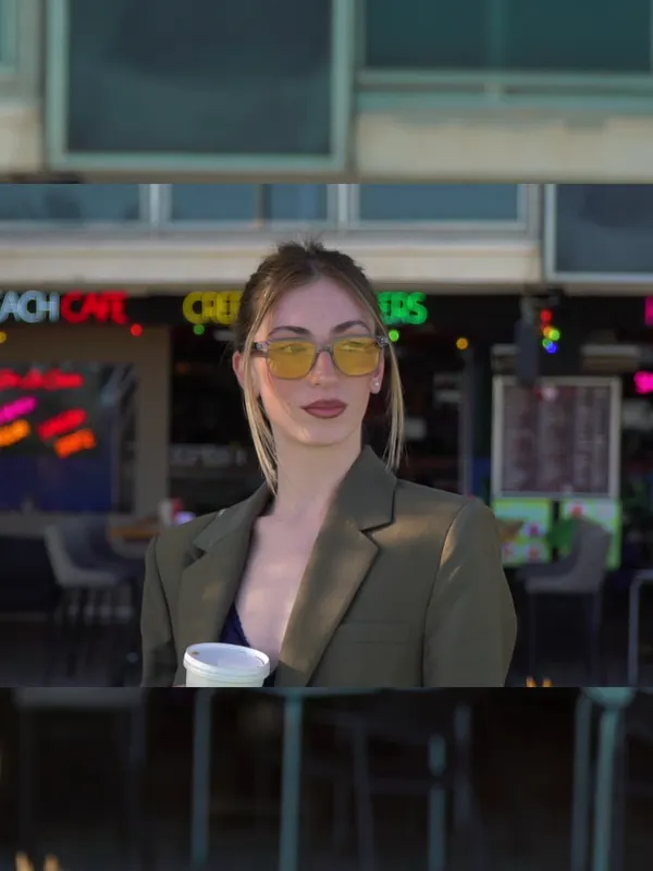 Mujer con gafas de cristales amarillos frente a una terraza con neones.