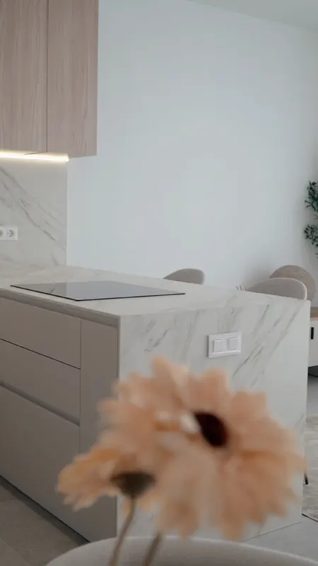 Isla de cocina de piedra blanca veteada, con una flor desenfocada en primer plano.